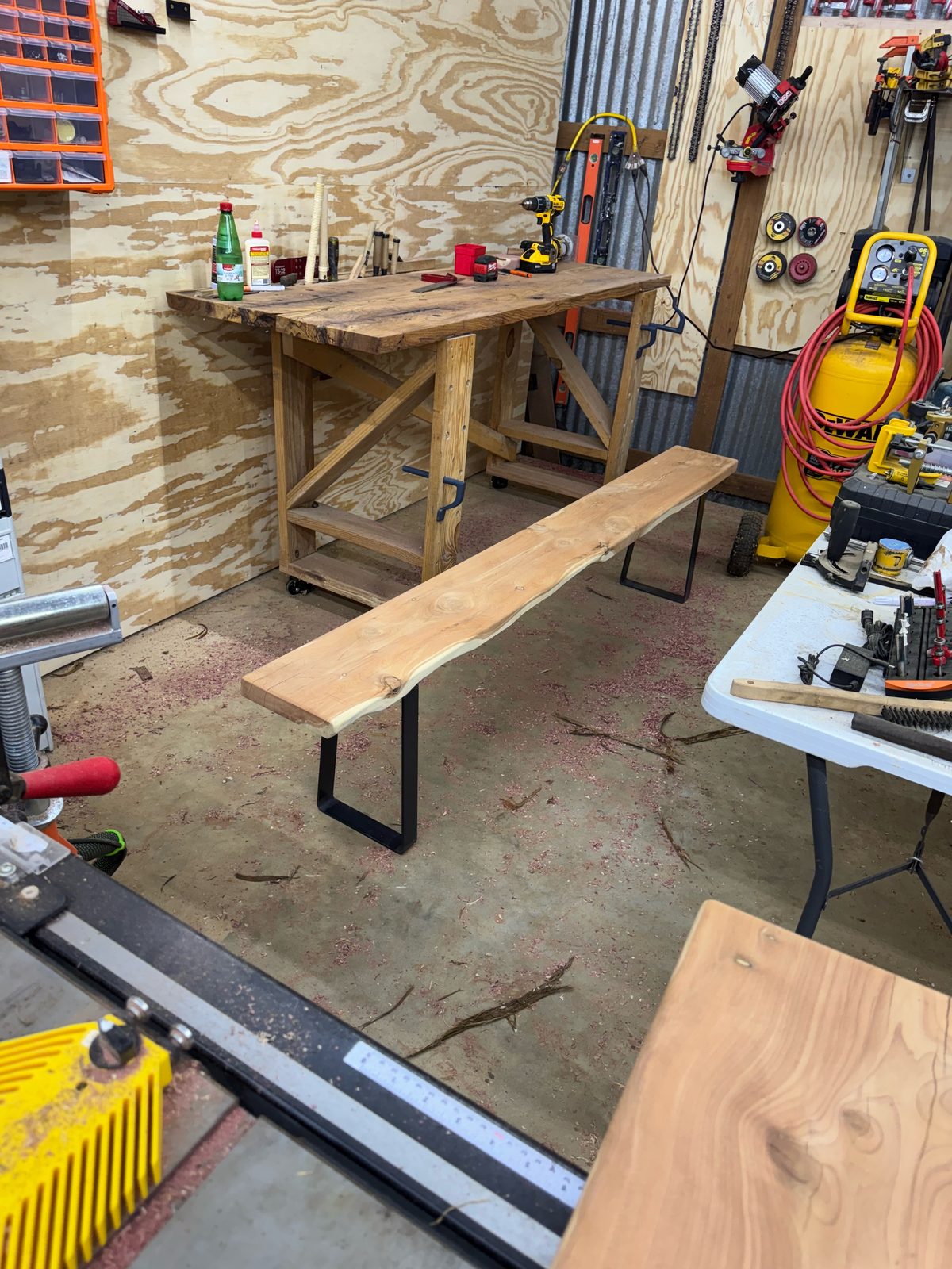 Finished live-edge eastern red cedar bench with black steel legs in the shop