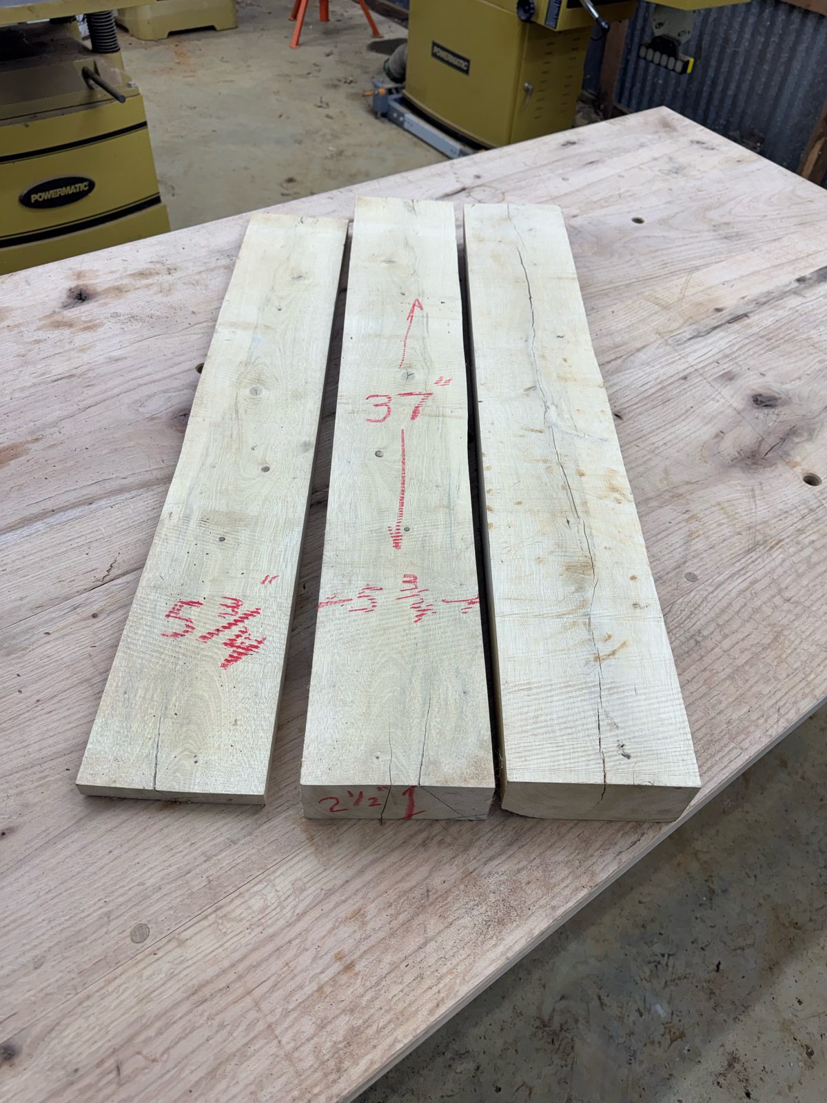 Three rough-sawn gum bumelia boards, lot GB001, on the shop table with red chalk measurements