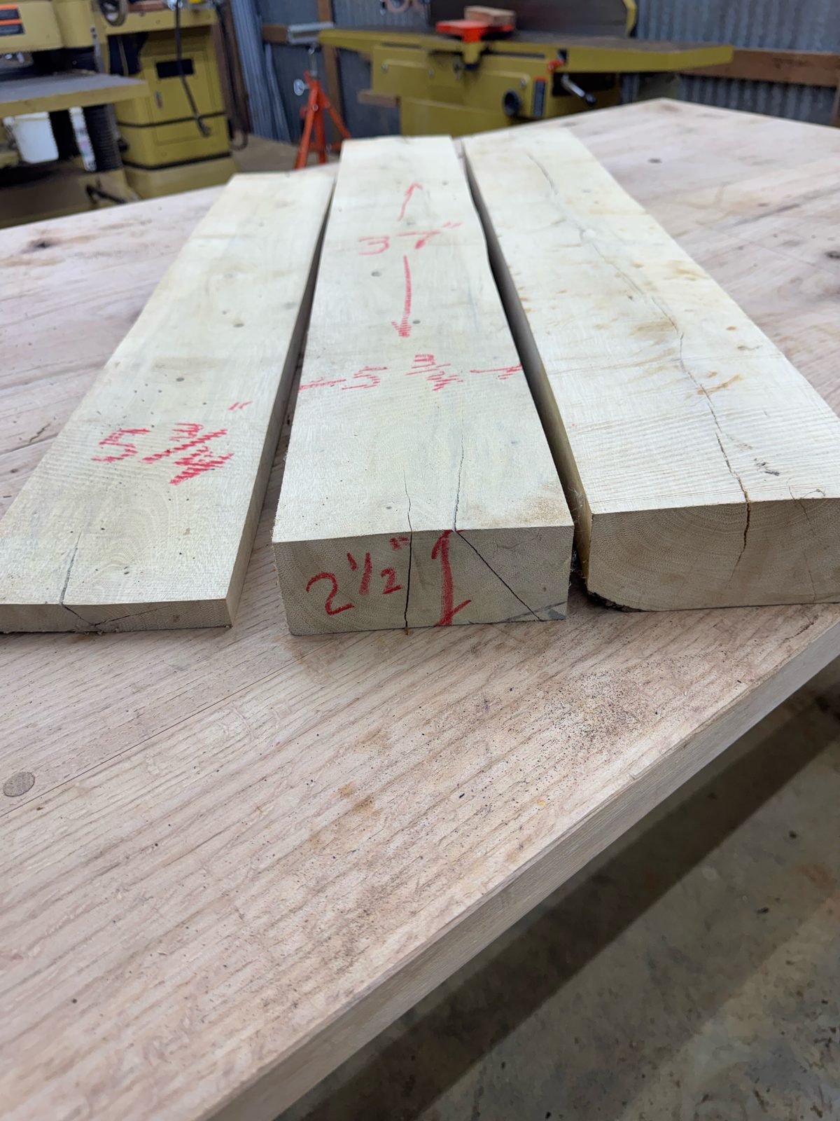 End grain of the GB001 gum bumelia boards marked 2-1/2 inches thick, showing end checks
