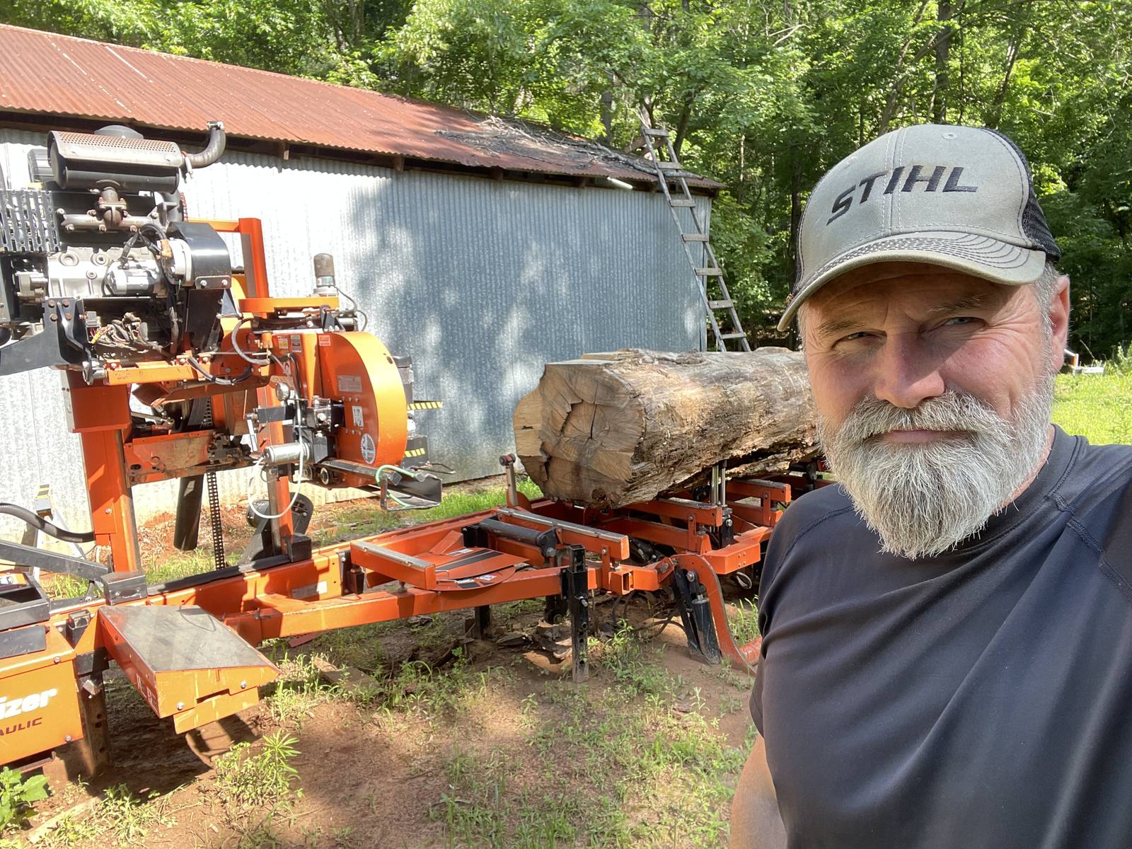 Portable sawmill with a log on the bed outside the mill shed