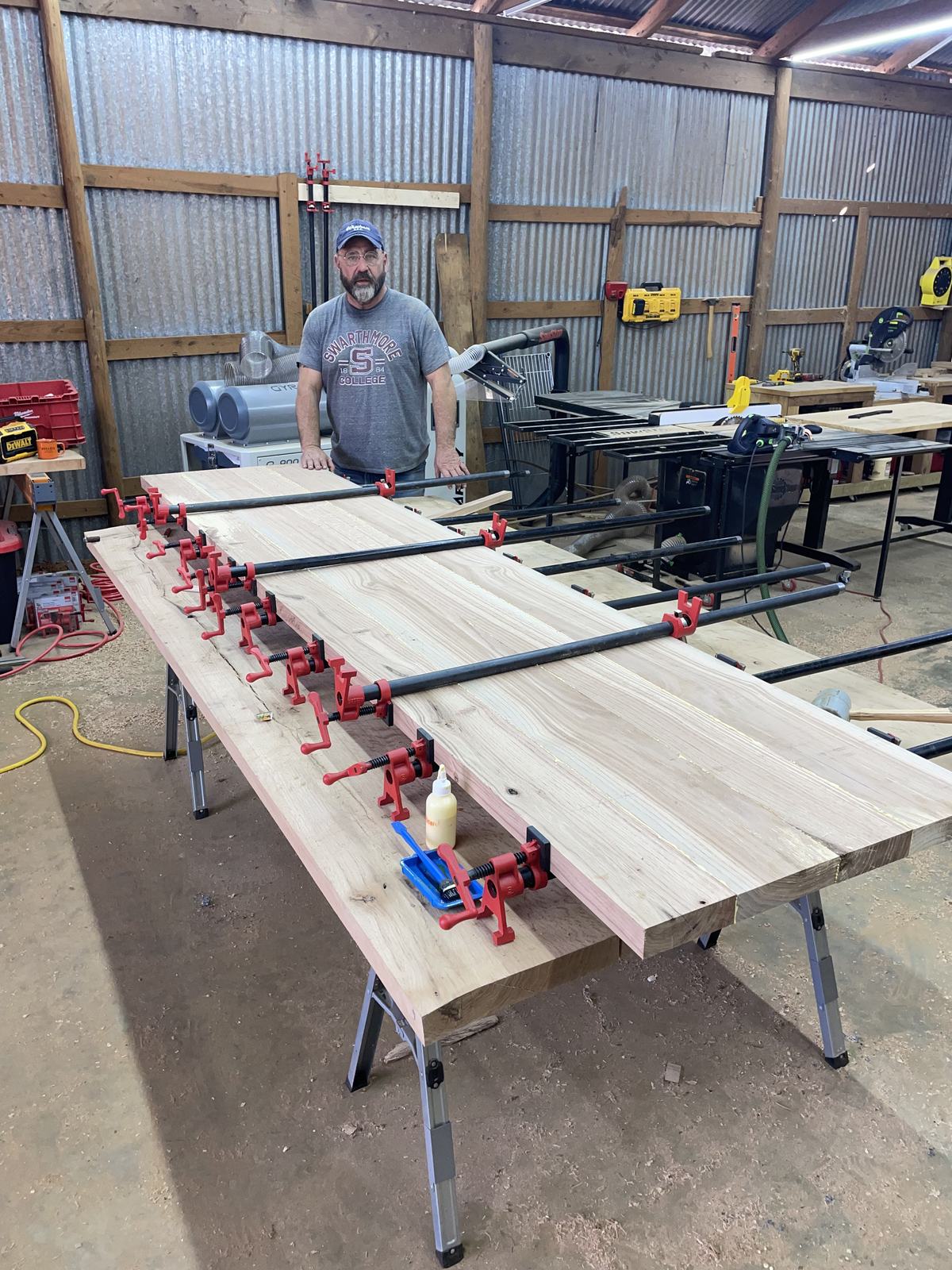 Wide panel glue-up held in pipe clamps on sawhorses in the shop